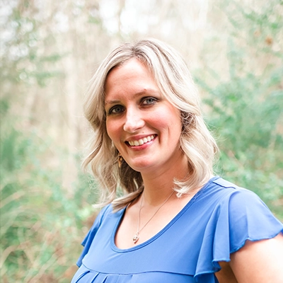 Beth Liles smiling outside, with greenery in the background.